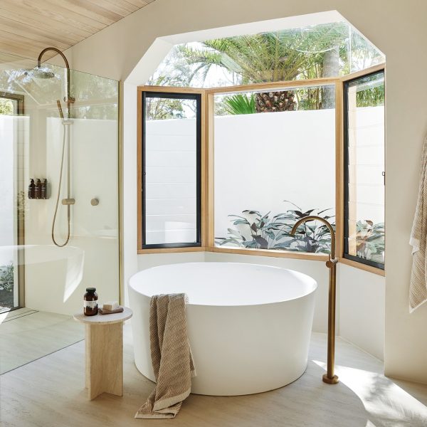 Bathroom featuring limestone tiles, large windows around a circular bathtub